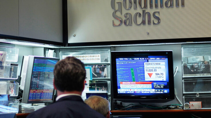 Financial professionals sit in the Goldman Sachs booth on the floor of the New York Stock Exchange